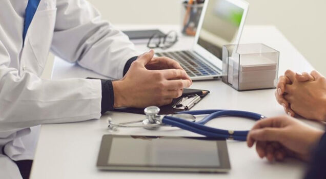 Consulta médica com laptop e estetoscópio na mesa
