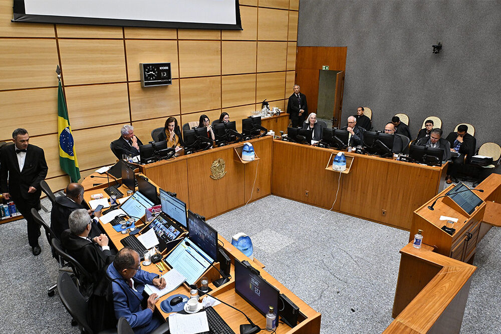 Reunião da câmara legislativa com representantes e painel eletrônico.