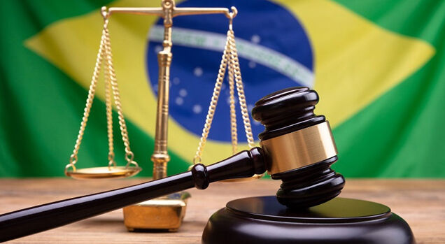 Martelo de juiz e balança sobre a bandeira do Brasil